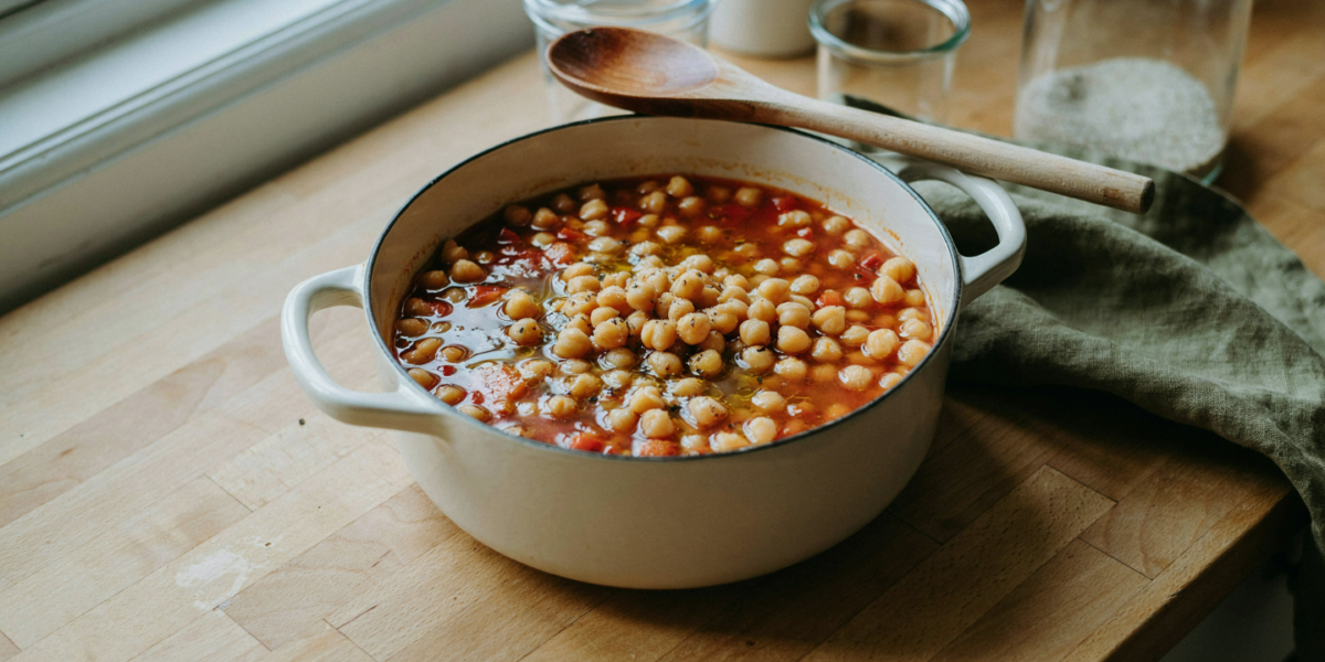 A pot of thick chickpea and pasta stew with olive oil and black pepper
