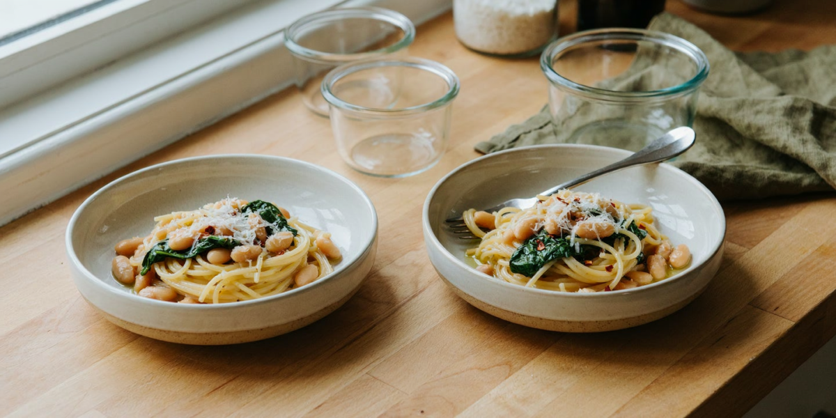 Spaghetti with garlic oil, white beans and spinach in a bowl