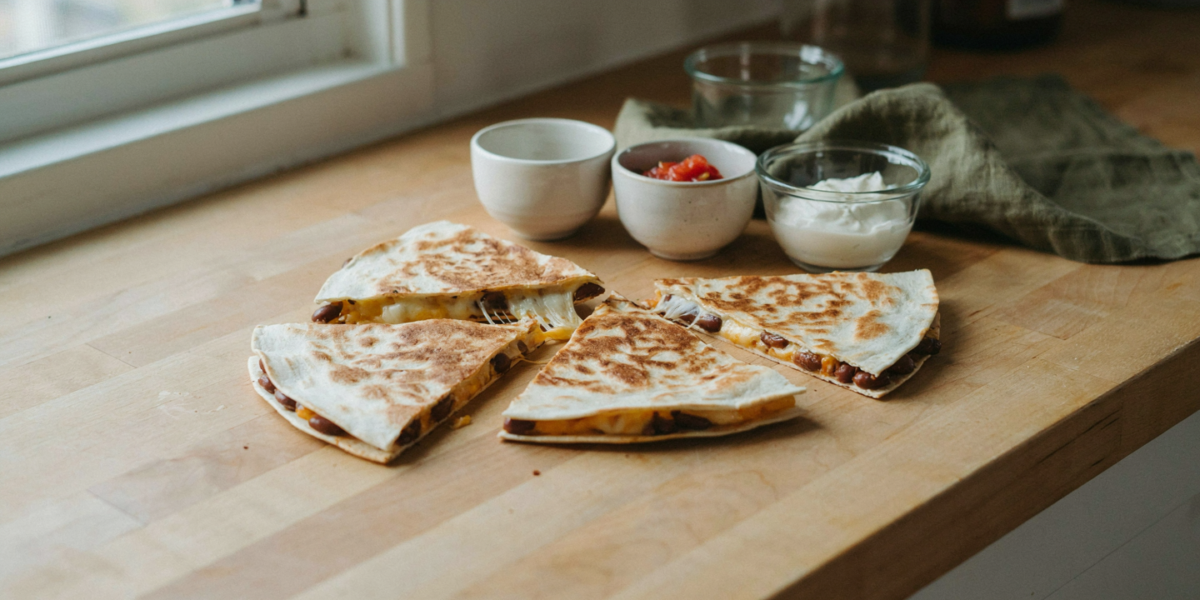 Crisp black bean quesadillas cut into wedges with salsa and sour cream
