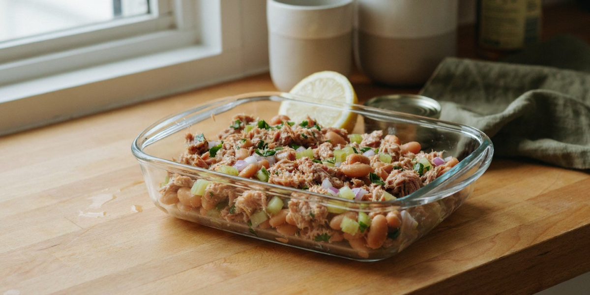 Tuna and white bean salad with celery and parsley in a glass container